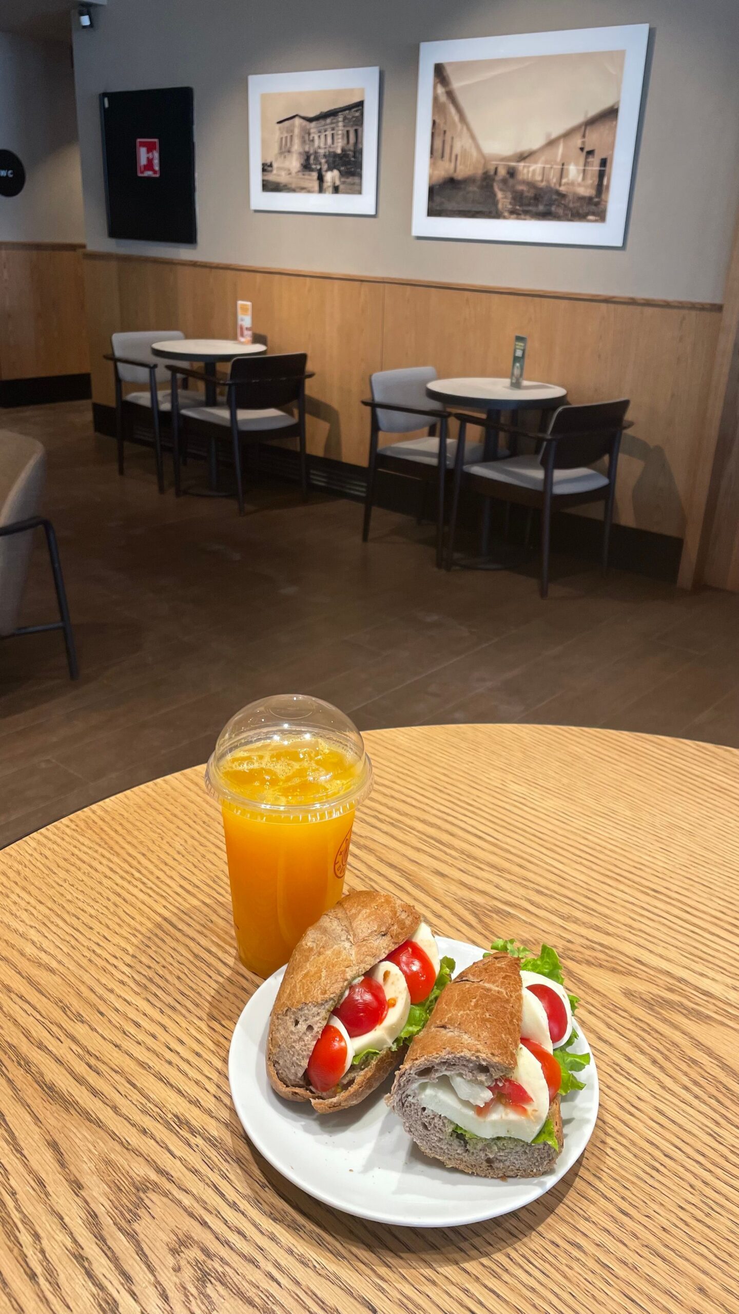 Delicious caprese sandwich with mozzarella, tomatoes, and lettuce served with fresh orange juice.